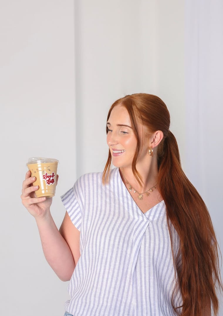 A barista holding a branded iced drink beside the cart.
