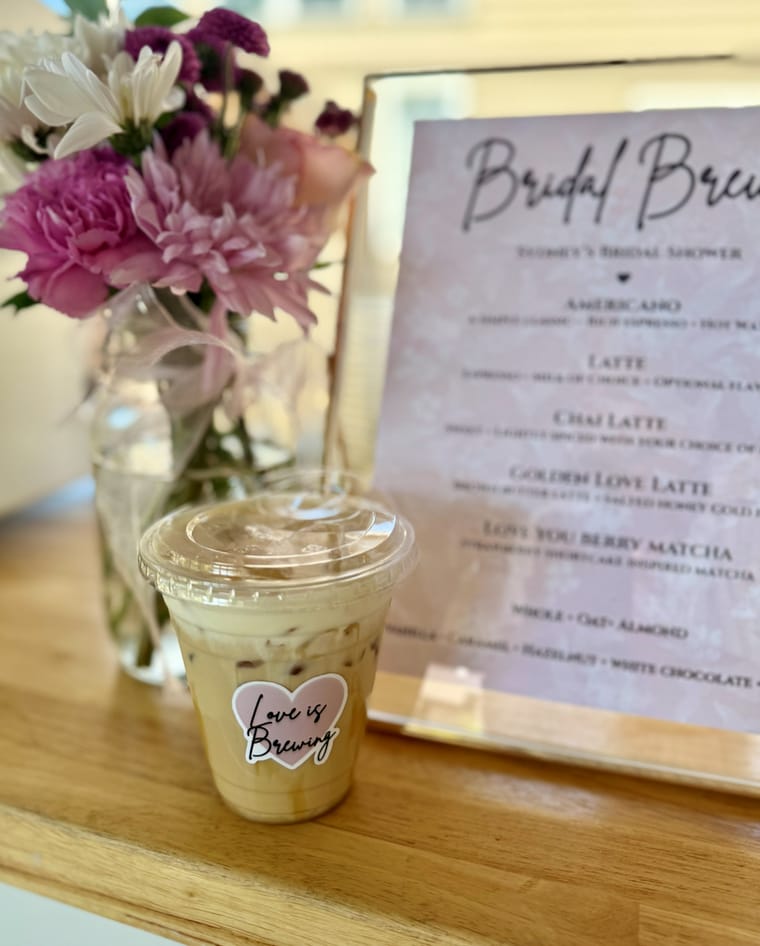 A framed custom Bridal Brews menu beside an iced drink and fresh flowers.