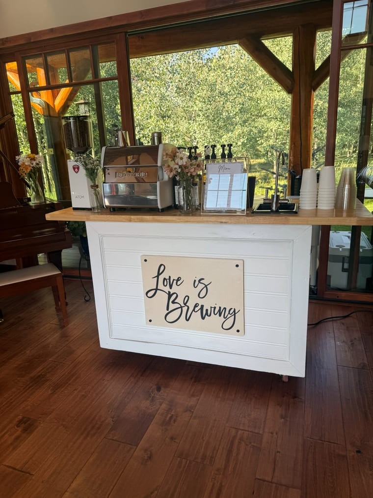 The cart with a Love is Brewing sign at an indoor venue.