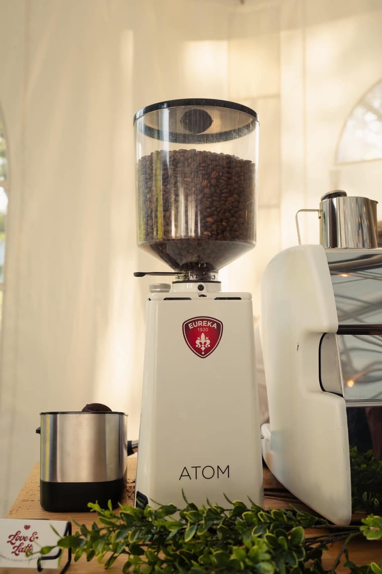 An espresso grinder full of beans on the cart.