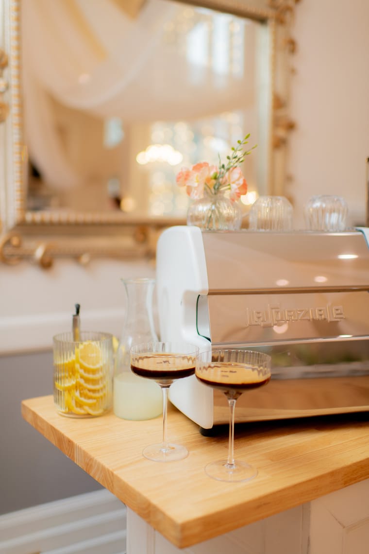 The espresso machine on the cart with two finished drinks in front of it.