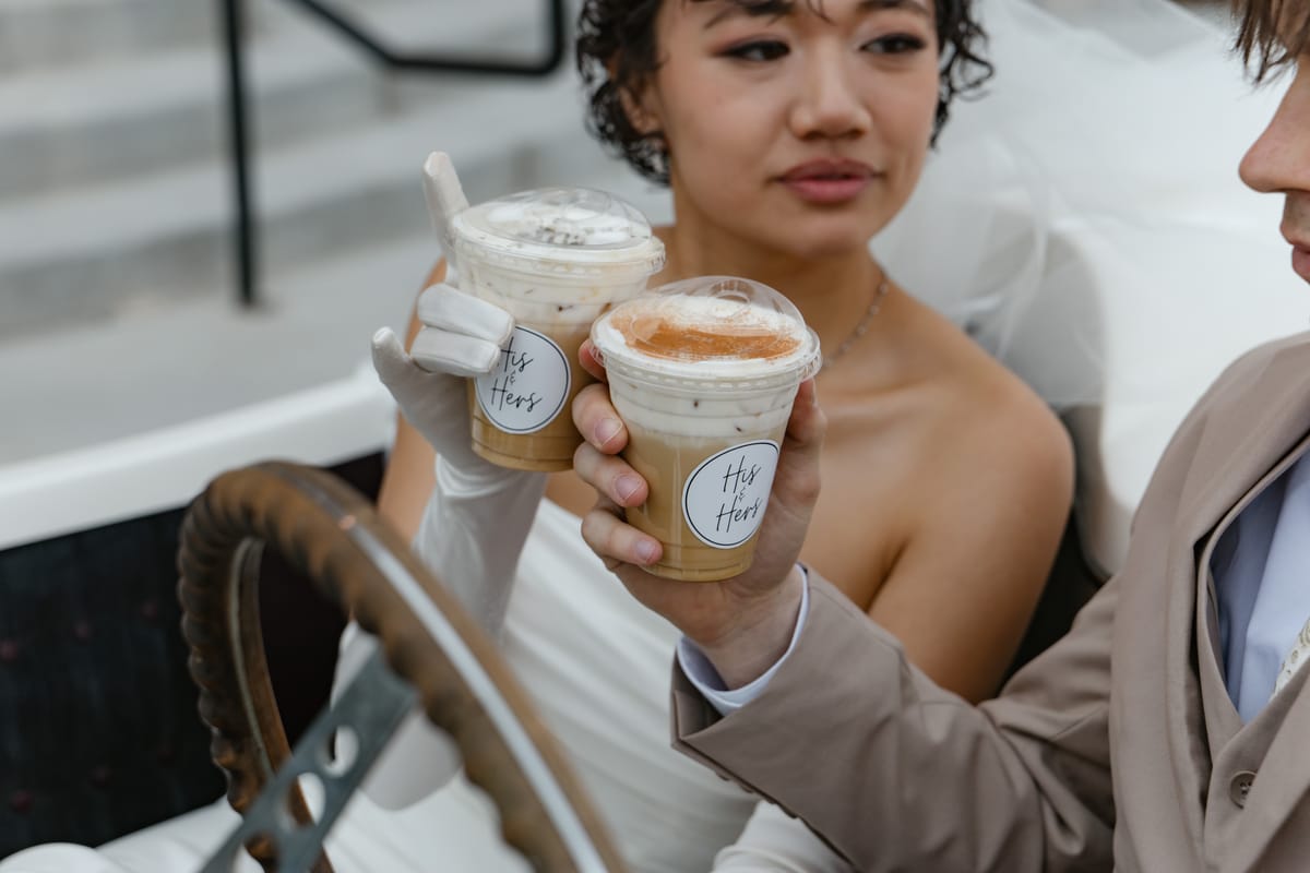 A bride holding two iced drinks in branded Love and Latte cups.
