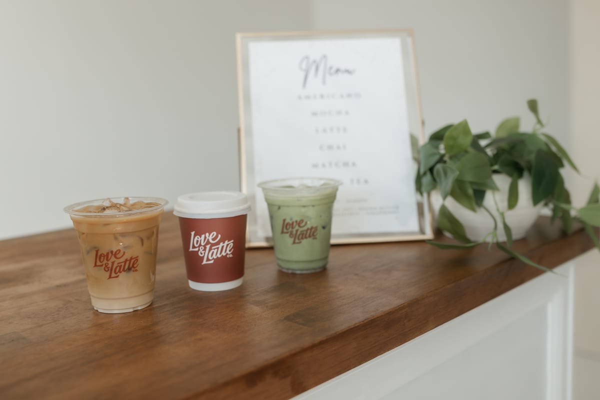 Three finished iced drinks lined up on the cart beside a printed menu