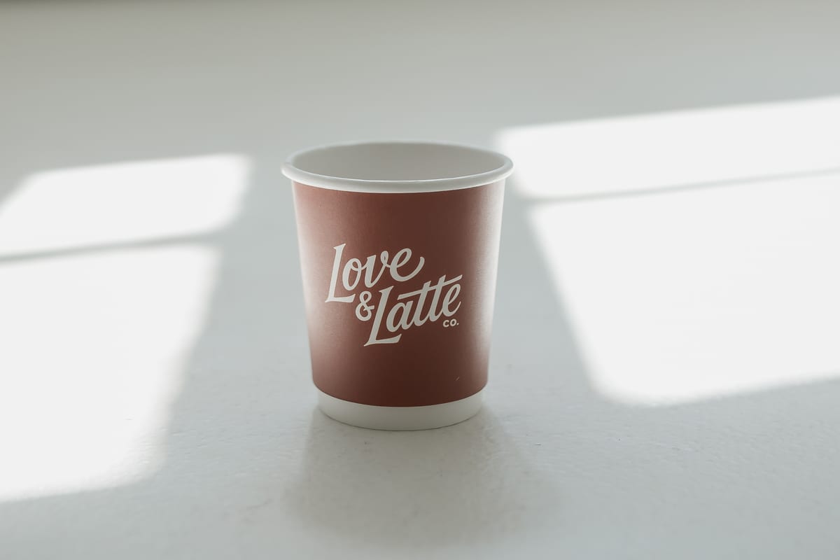 An empty branded Love and Latte cup on a white surface.