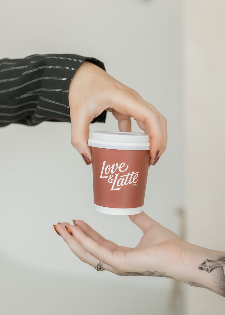 A branded cup being handed from one person to another