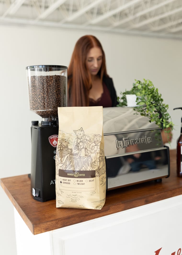 The espresso machine and grinder on the cart with a bag of locally roasted coffee.
