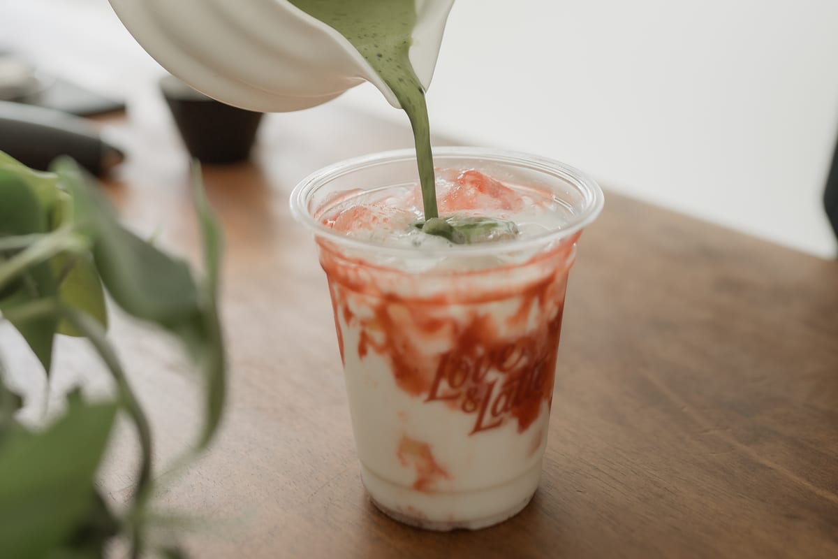Matcha being poured over ice into a clear cup.