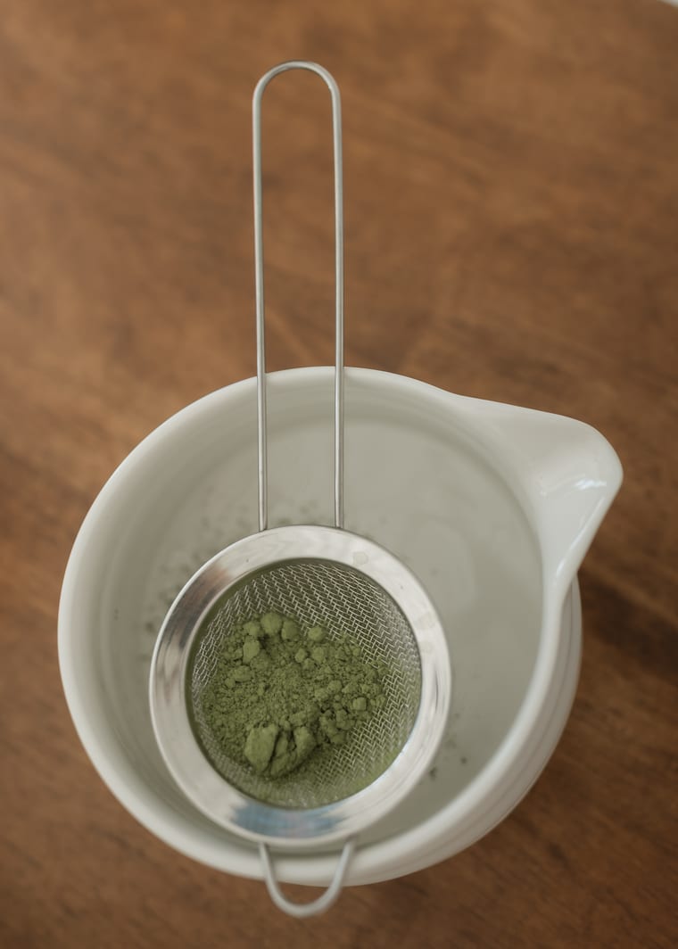 Matcha powder being sifted into a bowl.