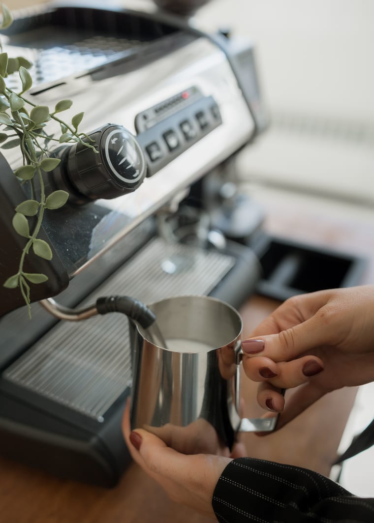 Milk being steamed in a jug at the espresso machine.