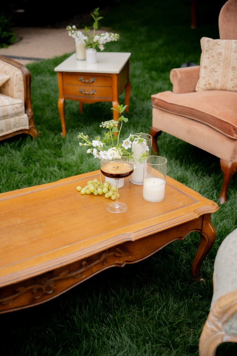 An outdoor lounge setup with drinks on a wooden table at a wedding.
